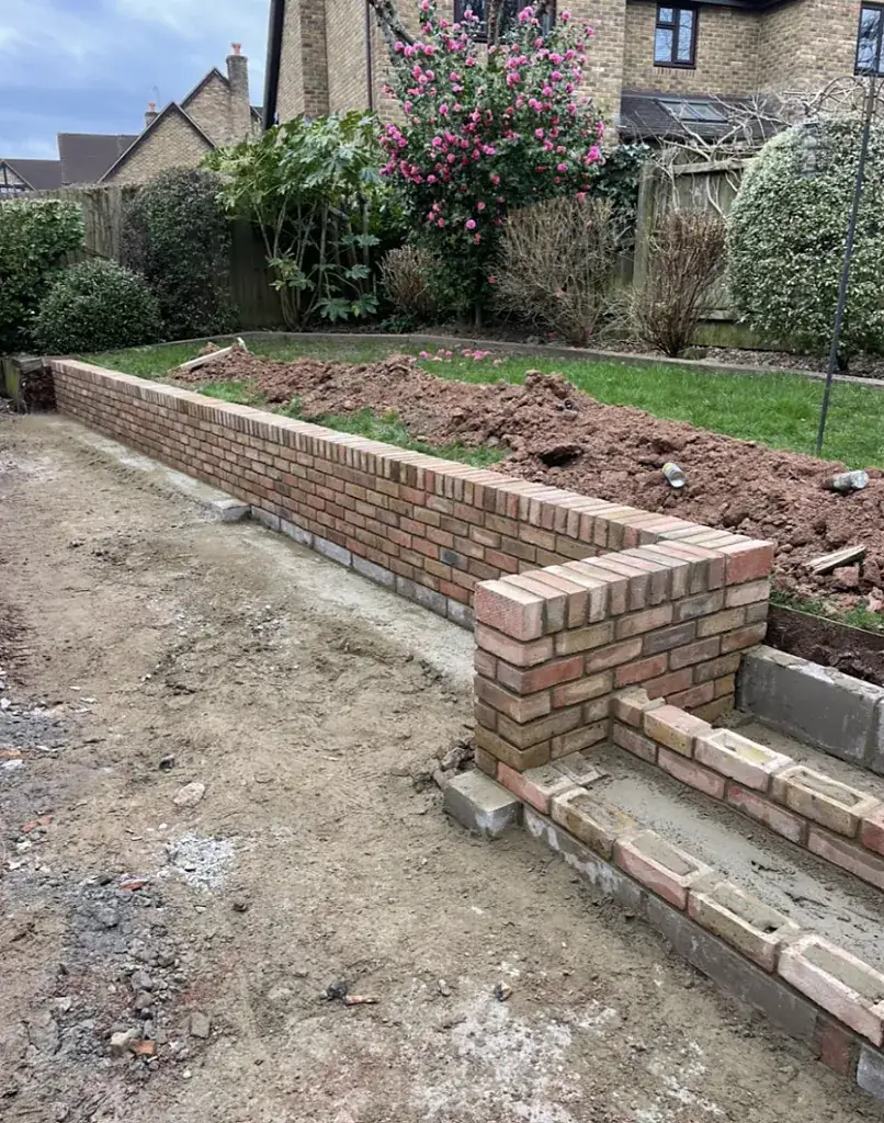 New brick retaining wall holding back a sloping garden