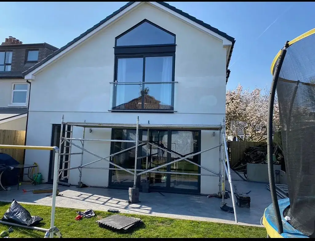 House with scaffolding in place while a large glazed extension is installed
