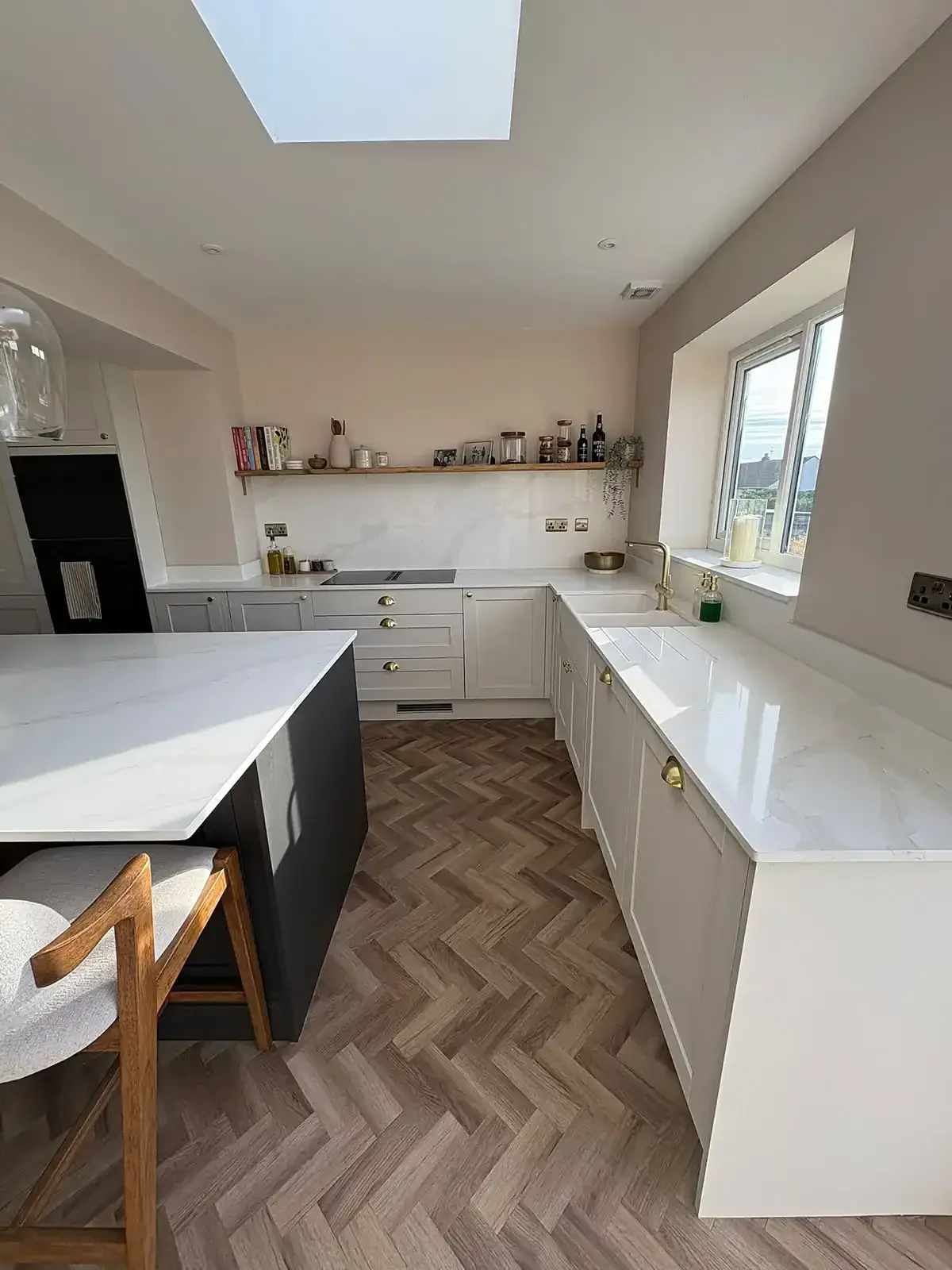 Finished kitchen with a dark island, pale cabinetry and a herringbone floor