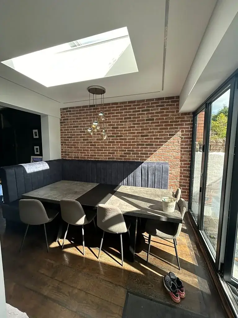 Dining area in an extension with exposed brick and a built-in banquette seat