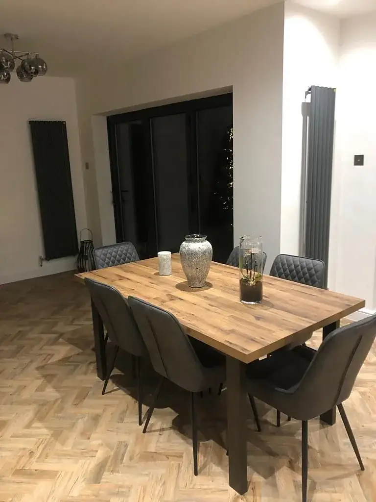 Dining room with an oak table, dark chairs and a herringbone floor