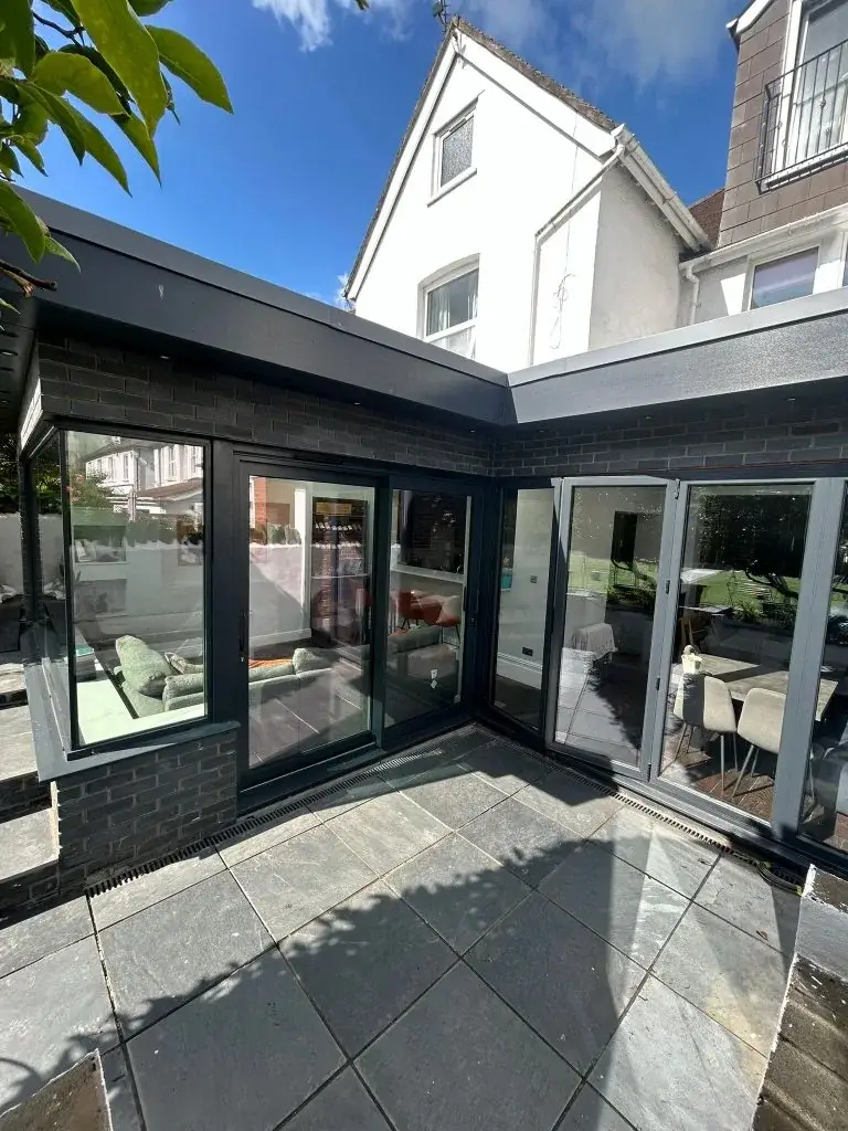 Dark-framed extension with glazed doors on both sides of a corner