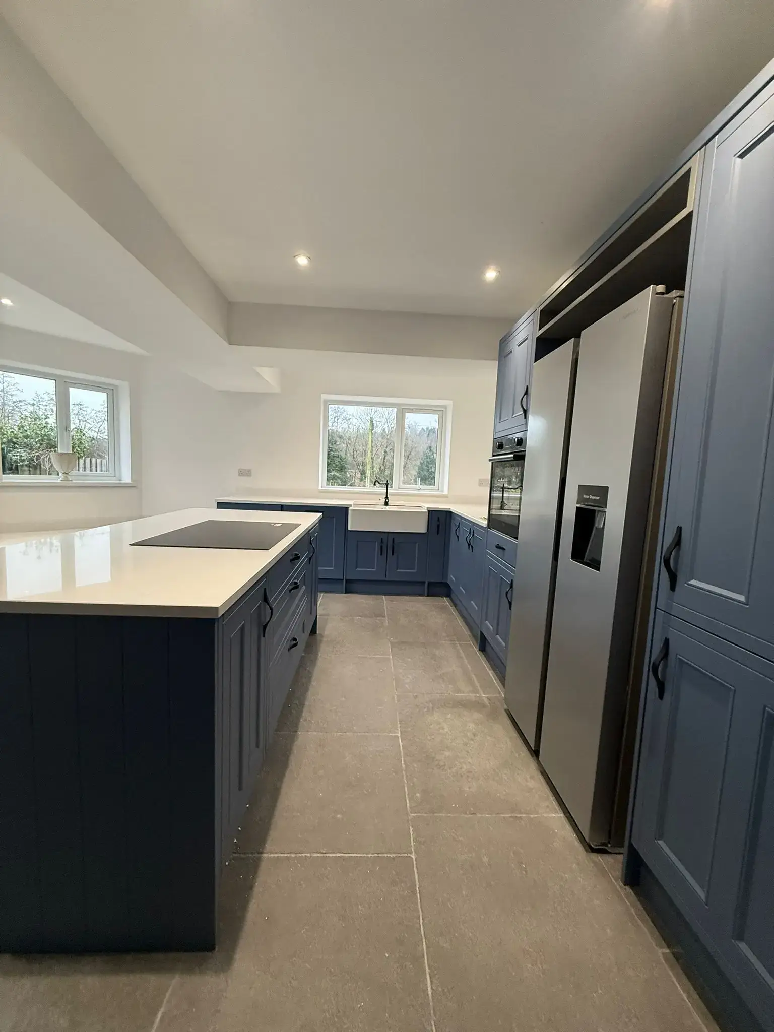 Navy shaker kitchen with a stone-topped island and a large-format tiled floor