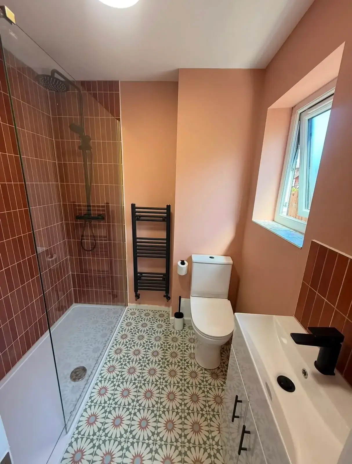 Shower room with terracotta wall tiles, a walk-in shower and a patterned tile floor