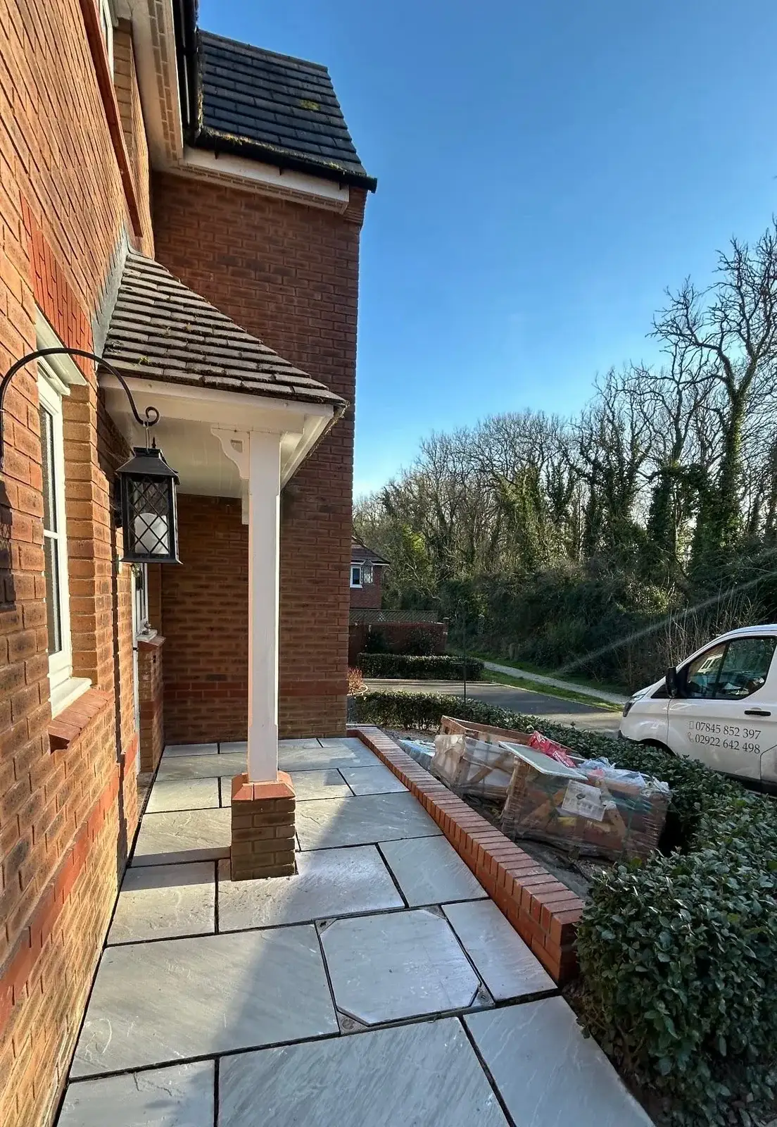 Stone paving laid along the side of a house, edged with a low brick wall