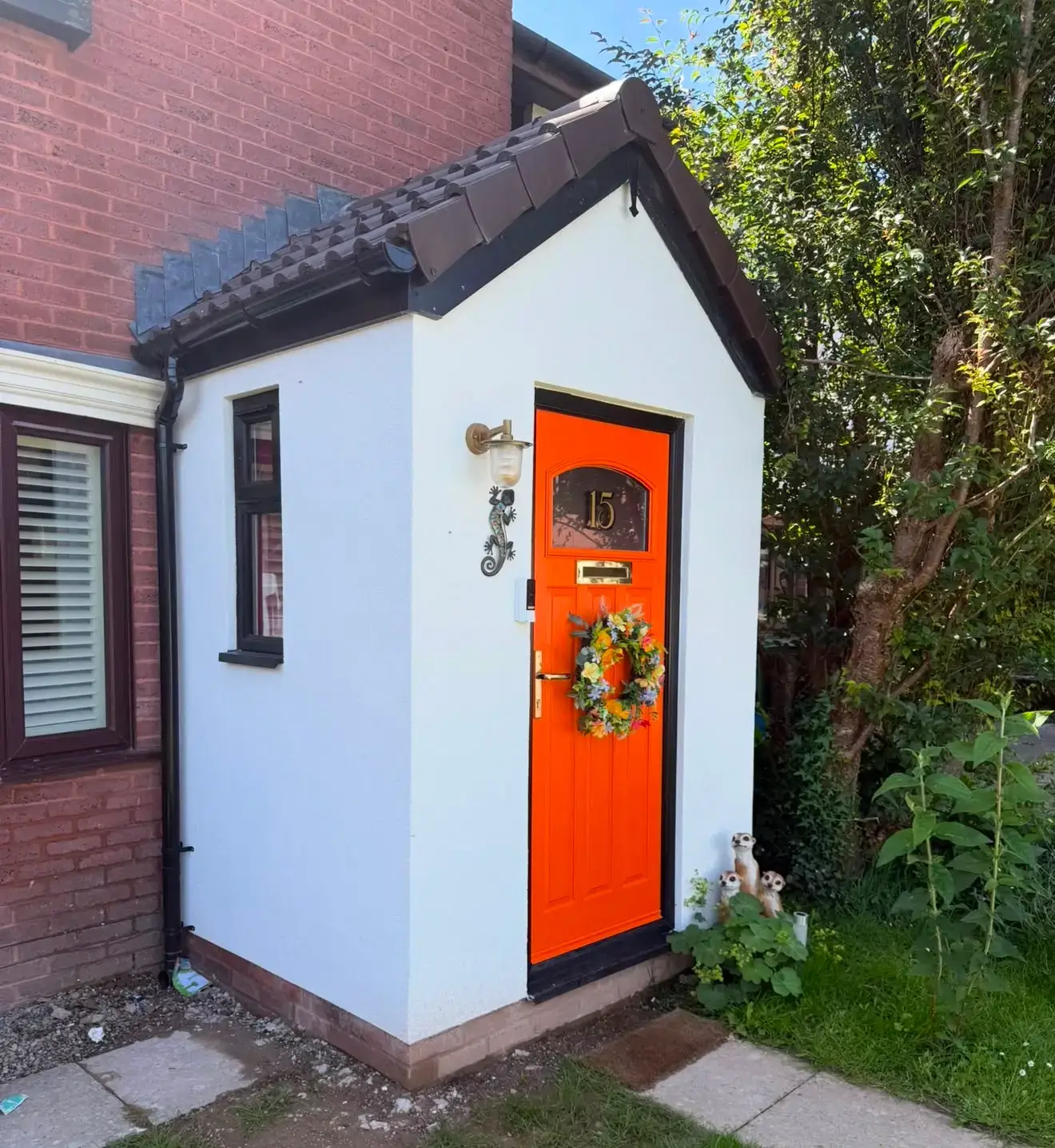 New white porch extension with a bright orange front door