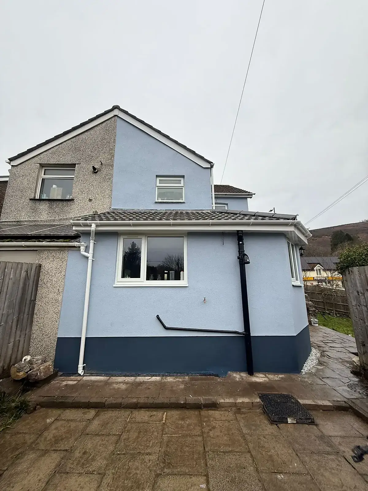 Rear of a house re-rendered and painted, with a tiled-roof extension