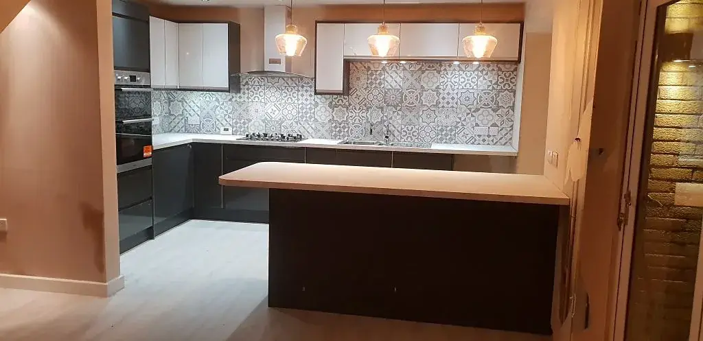 Renovated kitchen with dark units, a patterned tile splashback and a breakfast bar