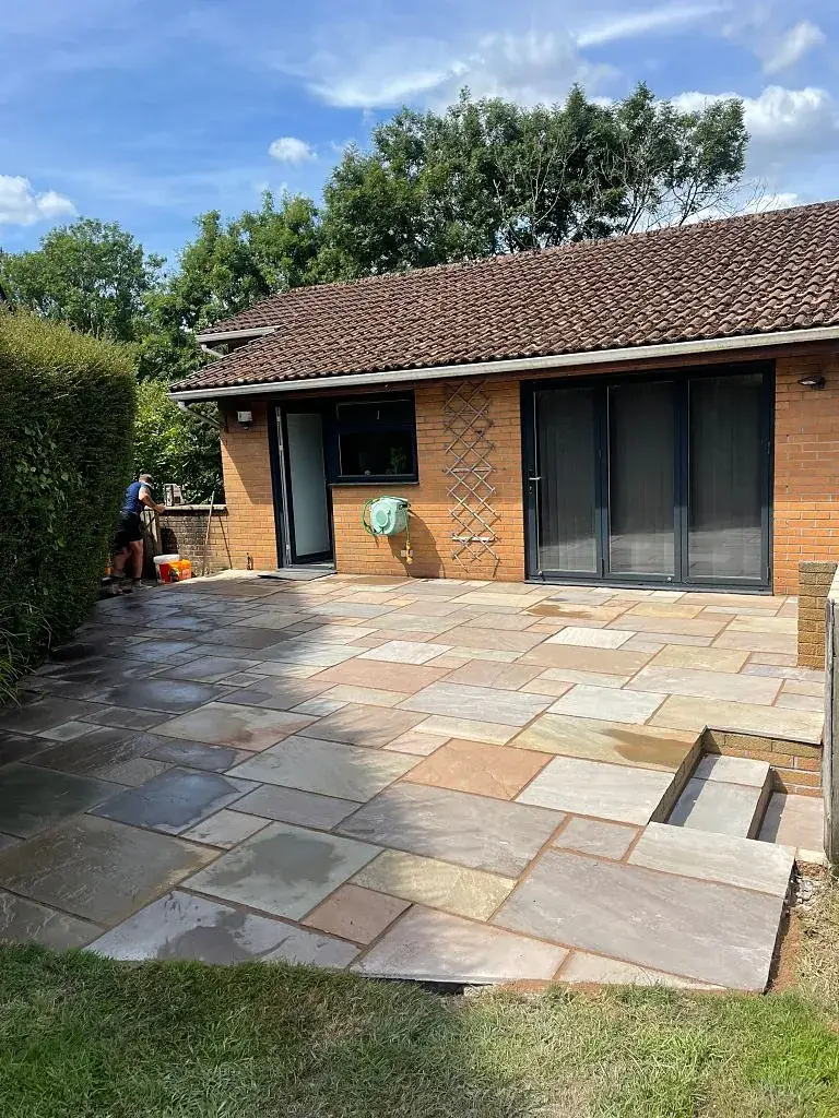Bungalow with grey bi-fold doors opening onto an Indian sandstone patio