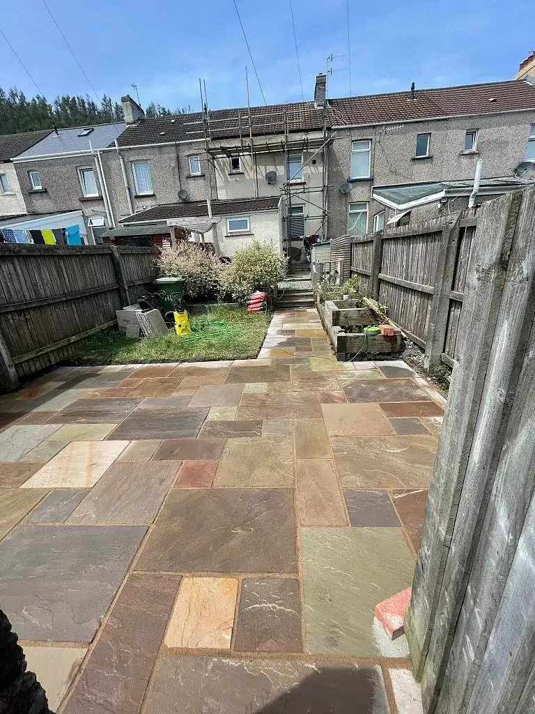 Sandstone patio with steps leading down into a long garden